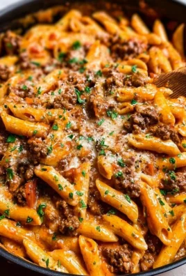 A creamy beef pasta dish served in a bowl, garnished with herbs.