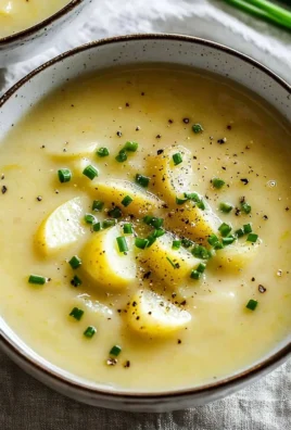 A bowl of creamy potato leek soup garnished with fresh herbs.