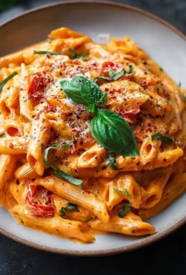 Creamy tomato pasta dish garnished with fresh herbs and served in a bowl.