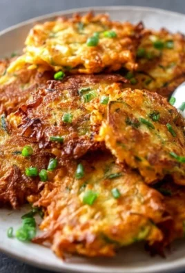Crispy vegetable fritters served on a plate, garnished with herbs.