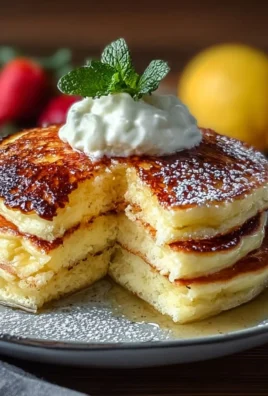 Fluffy lemon ricotta pancakes topped with syrup and fresh berries