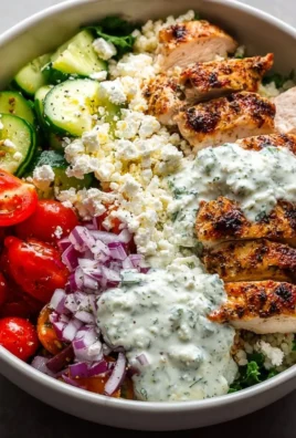 Delicious Greek chicken bowl topped with fresh vegetables and feta cheese