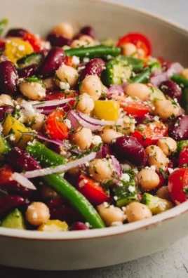 Lemony Greek bean salad with fresh vegetables and herbs in a bowl