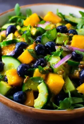 Mango Cucumber Salad with Blueberry and Avocado garnished with fresh herbs