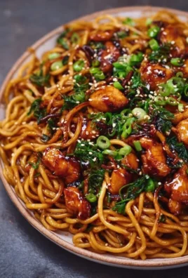 Delicious sticky garlic chicken noodles served in a bowl topped with green onions
