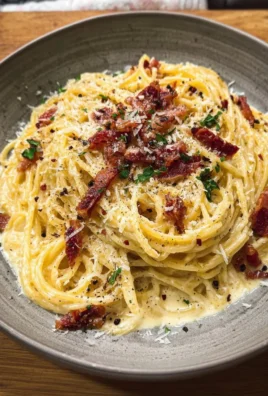 Delicious creamy spaghetti carbonara topped with parmesan cheese and pepper.
