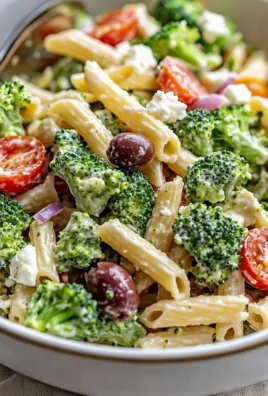 A vibrant bowl of broccoli pasta salad with fresh vegetables and dressing.