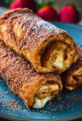 Cinnamon Sugar French Toast Roll-Ups on a plate garnished with syrup and fruit