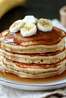 A plate of fluffy banana pancakes topped with syrup and banana slices