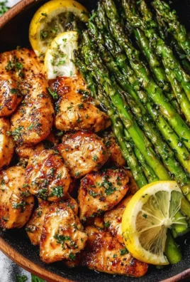 Garlic butter chicken bites served with lemon asparagus on a plate.