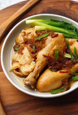 Delicious ginger poached chicken drumsticks garnished with herbs on a plate.