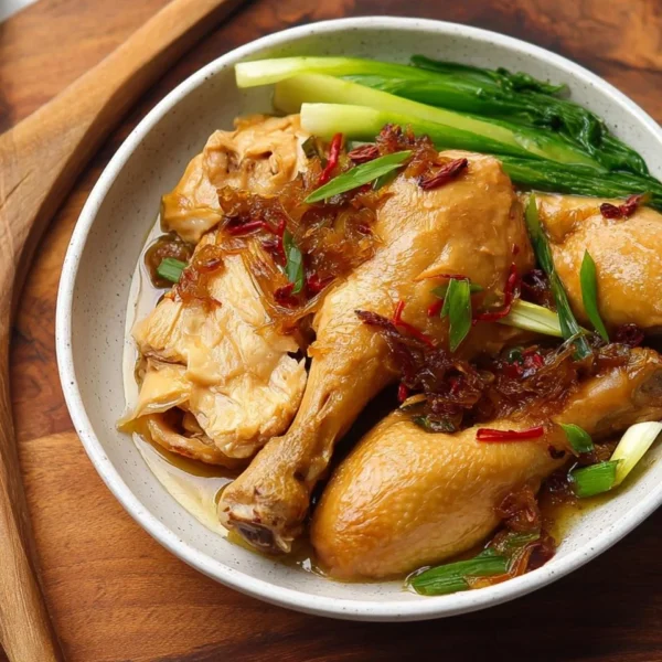 Delicious ginger poached chicken drumsticks garnished with herbs on a plate.