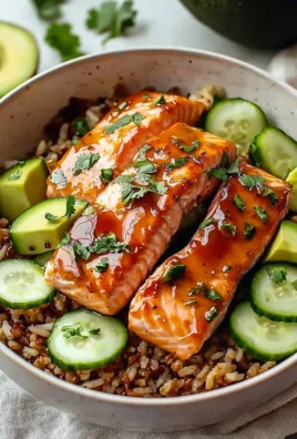 A colorful honey glazed salmon bowl topped with vegetables and garnished with herbs.