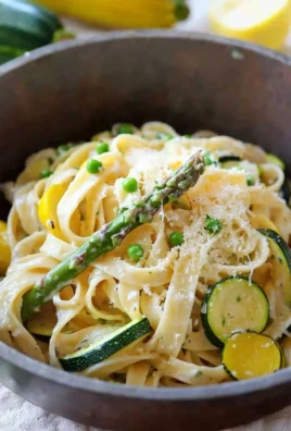 Plate of colorful vegetable pasta with fresh vegetables and herbs