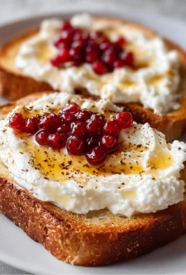 Whipped ricotta honey toast topped with honey and fresh fruit on a wooden table.