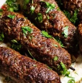 Plate of flavorful beef kofta served with dipping sauce and garnishes