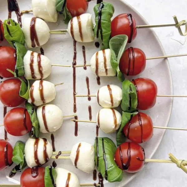 Delicious Caprese salad skewers with bocconcini, cherry tomatoes, and basil.