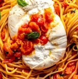 Bowl of cherry tomato pasta topped with fresh basil and parmesan cheese