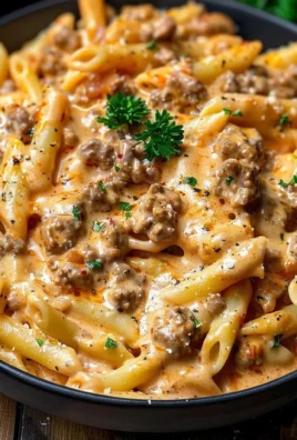 Creamy beef pasta dish garnished with herbs and served in a bowl.