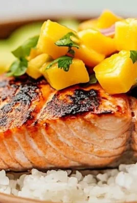 Grilled salmon fillet served with vibrant mango salsa on a plate.