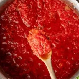 A bowl of homemade marinara sauce with fresh herbs and tomatoes
