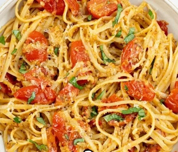 Plate of Linguine Positano garnished with fresh herbs and cherry tomatoes.