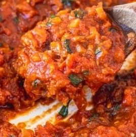 Fresh marinara sauce ingredients: tomatoes, garlic, herbs in a bowl.