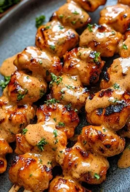 Bang Bang Chicken Skewers garnished with fresh herbs and spicy sauce