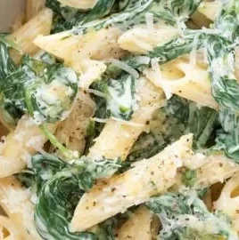 Pasta served with creamy spinach sauce topped with parmesan cheese