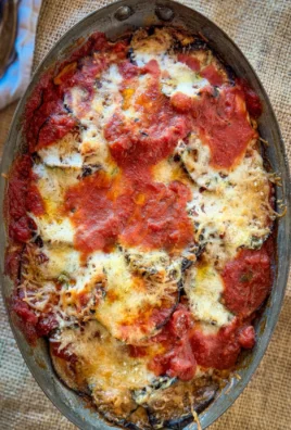 Plate of roasted eggplant parmesan with melted cheese and fresh herbs