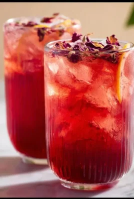 Refreshing Rose Hibiscus Iced Tea in a glass with ice and herbs.