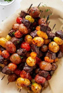 Rosemary garlic steak kebabs on a grill with vibrant vegetables