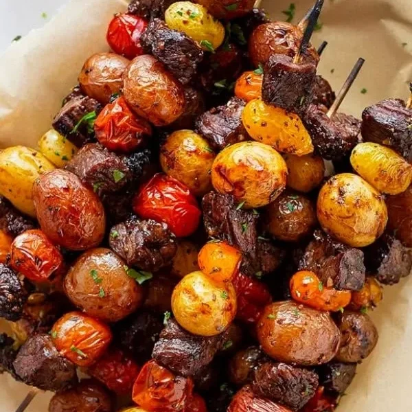 Rosemary garlic steak kebabs on a grill with vibrant vegetables