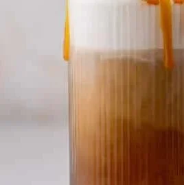 Homemade Salted Caramel Cold Brew beverage in a glass with cream and caramel drizzle