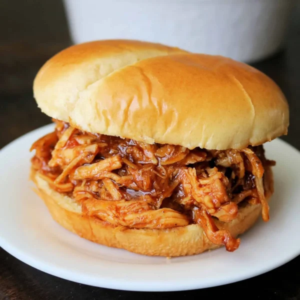 Delicious crockpot BBQ chicken served with sides on a wooden table