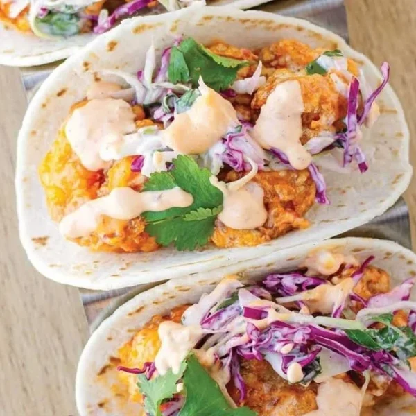 Delicious Bang Bang Shrimp Tacos served with fresh toppings and sauce