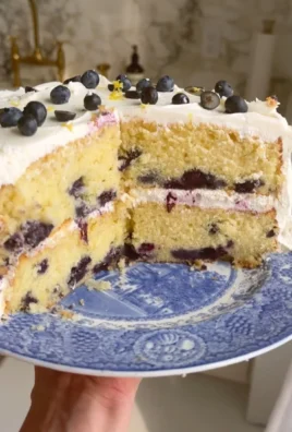 Slice of lemon blueberry cake with fresh blueberries and lemon zest decoration