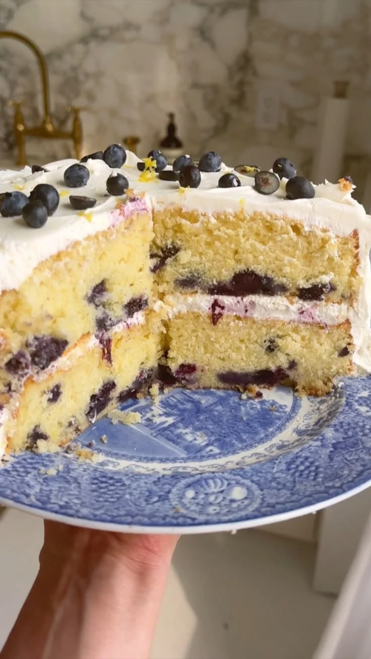 Slice of lemon blueberry cake with fresh blueberries and lemon zest decoration
