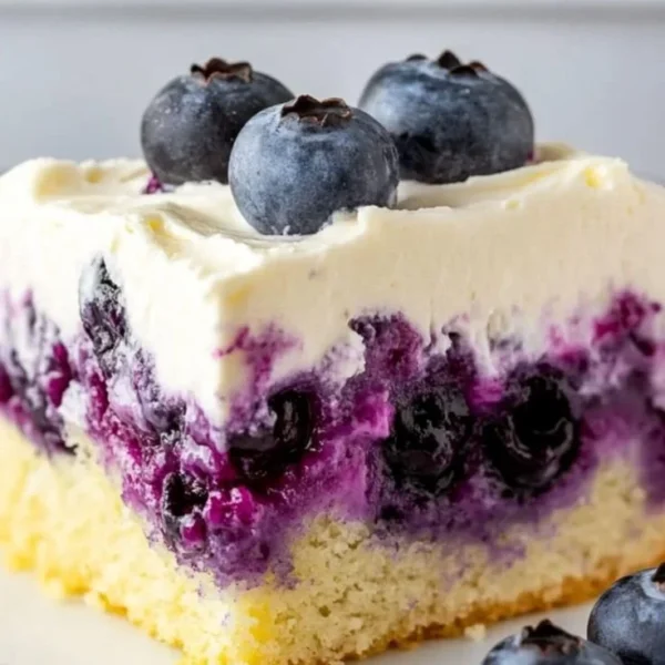 Delicious Lemon Blueberry Poke Cake topped with fresh blueberries and whipped cream