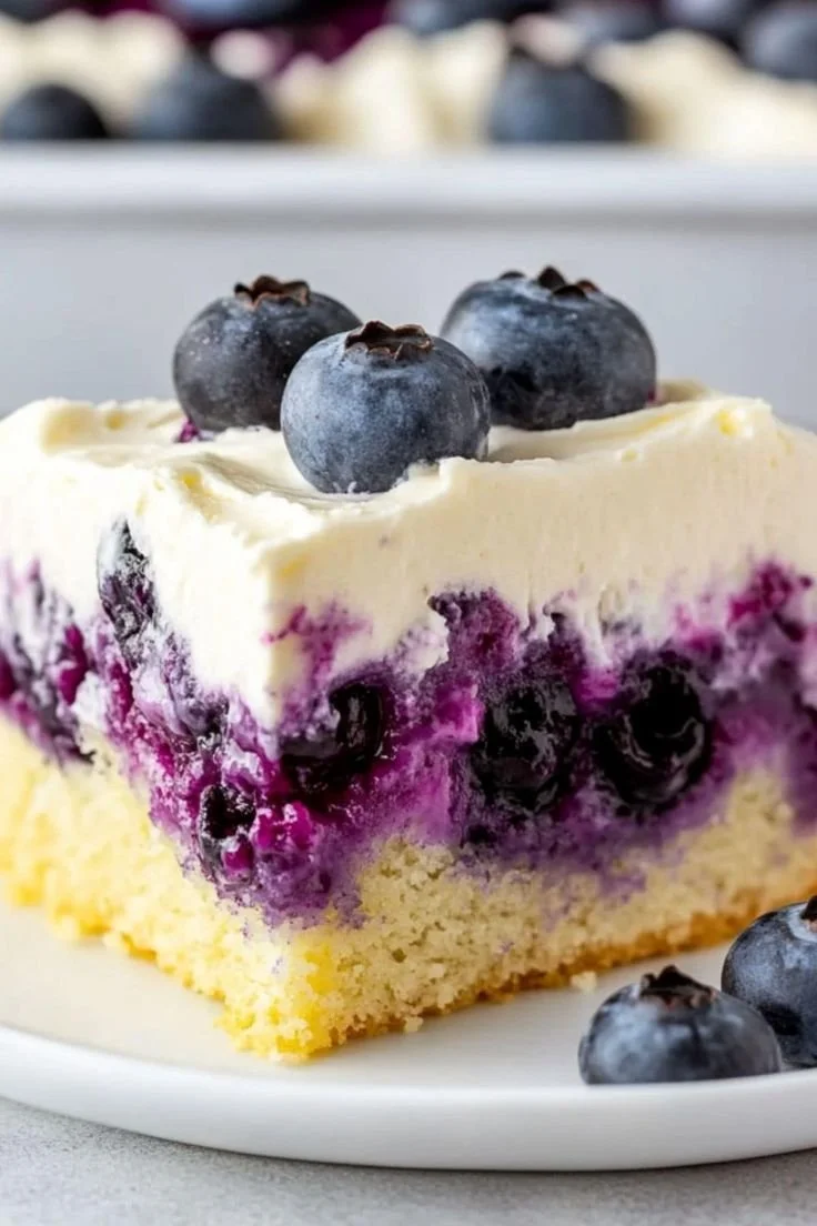 Delicious Lemon Blueberry Poke Cake topped with fresh blueberries and whipped cream
