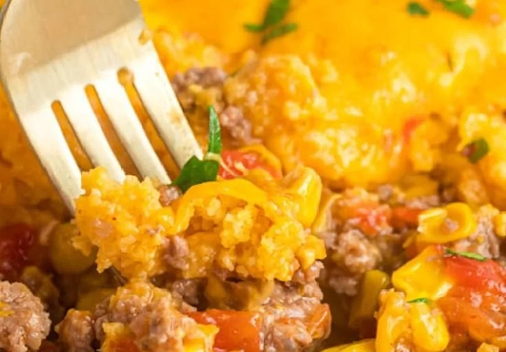 A hearty Mexican Cornbread Casserole topped with cheese and fresh ingredients.